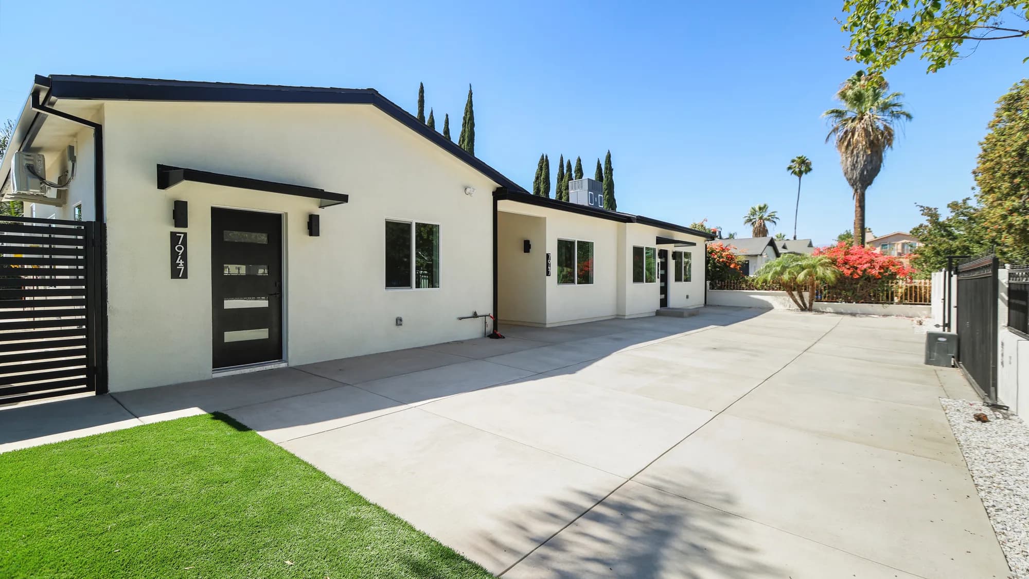 Completed single-story modern home by Build Tuff Construction in Los Angeles, with white stucco exterior, black-framed windows, and a wide concrete driveway