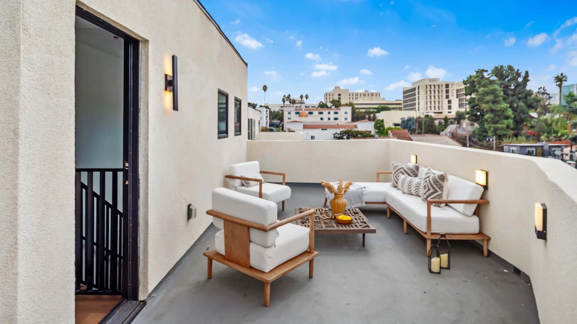 Modern rooftop terrace with white outdoor lounge furniture overlooking the Los Angeles skyline